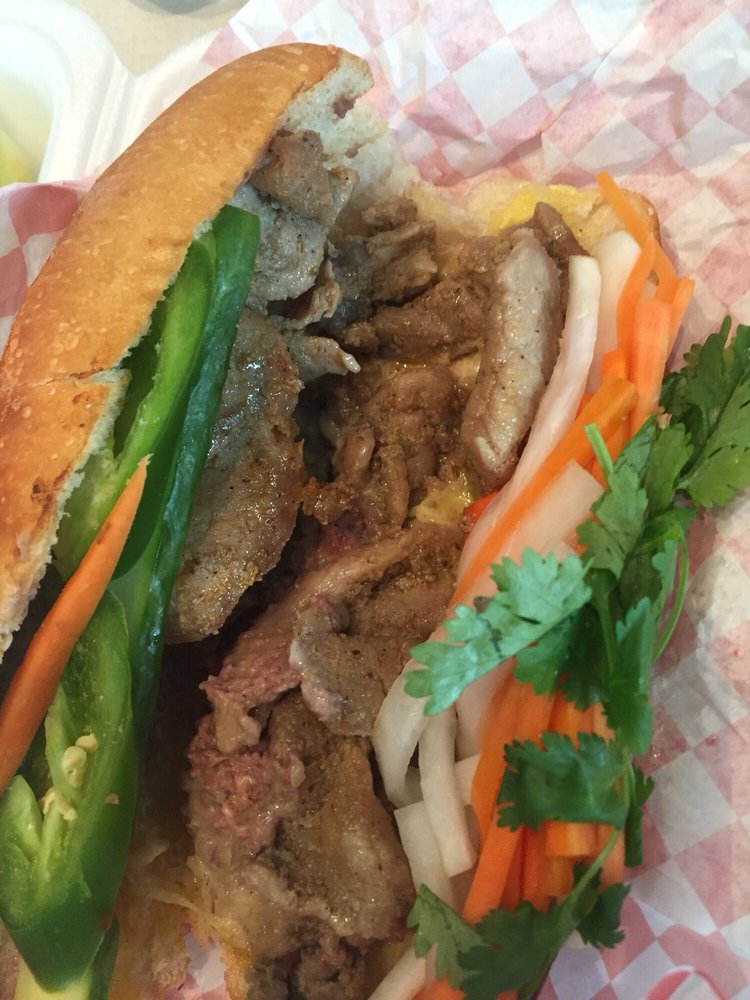 Close-up of a grilled meat bánh mì with jalapeño and cilantro